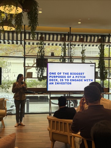 A speaker in front of a slide about using a pitch deck to engage with an investor.